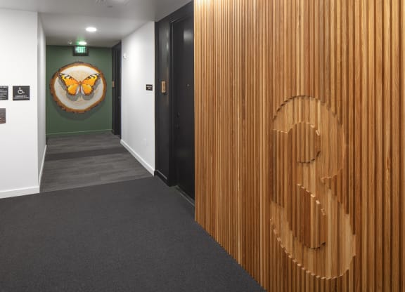 a hallway with black doors and a wooden wall with an owl on it at The Weidler in Portland, OR 97209