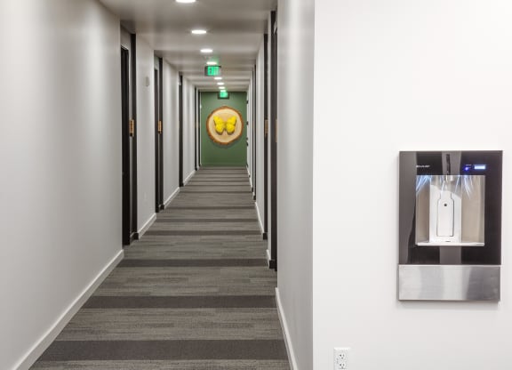 a hallway with a water dispenser and a yellow smiley face on the wall at The Weidler in Portland, OR 97209
