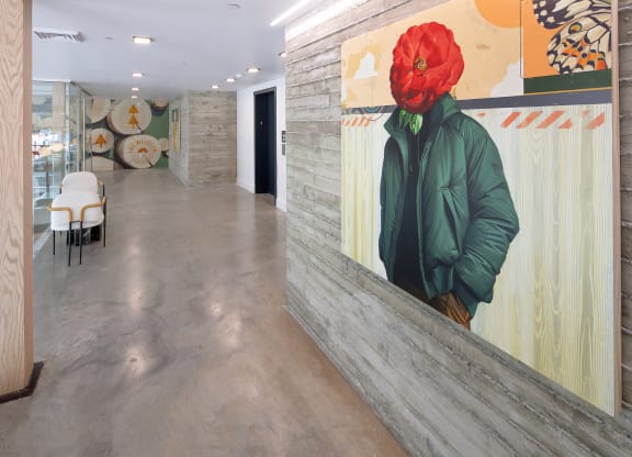 a large painting of a man wearing a red hat on a wall in a hallway at The Weidler in Portland, OR 97209