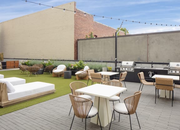 a rooftop patio with tables and chairs and a barbecue grill at The Weidler in Portland, OR 97209