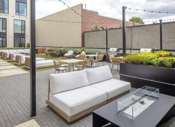 a rooftop patio with a white couch and tables and chairs at The Weidler in Portland, OR 97209