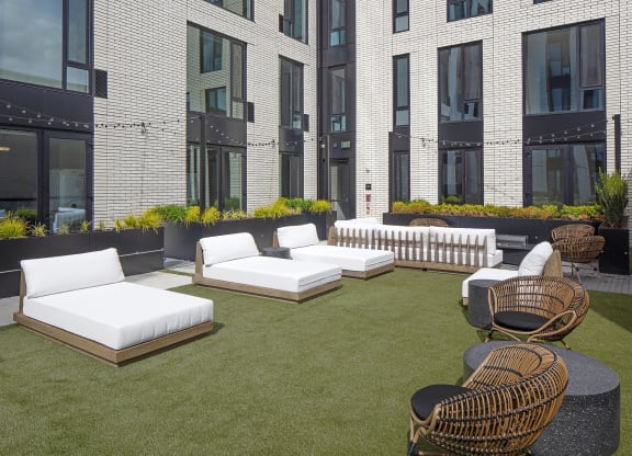 an outdoor lounge area of a building with white couches and chairs at The Weidler in Portland, OR 97209