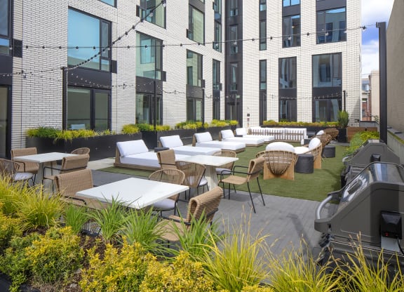 an outdoor patio area with tables and chairs at an apartment building at The Weidler in Portland, OR 97209