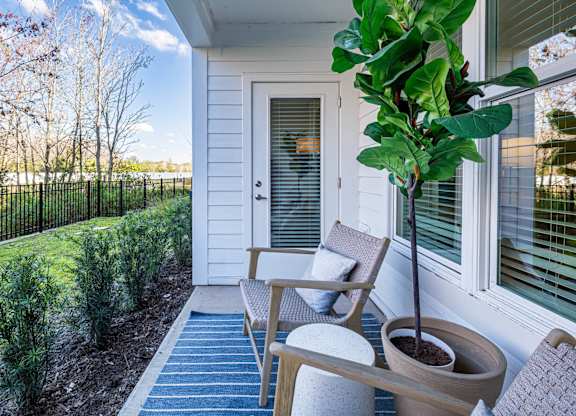 A small tree in a pot sits on a porch.