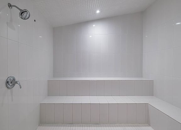 a white bathroom with a shower and white tiles  at Altis Grand Suncoast Apartments, Florida
