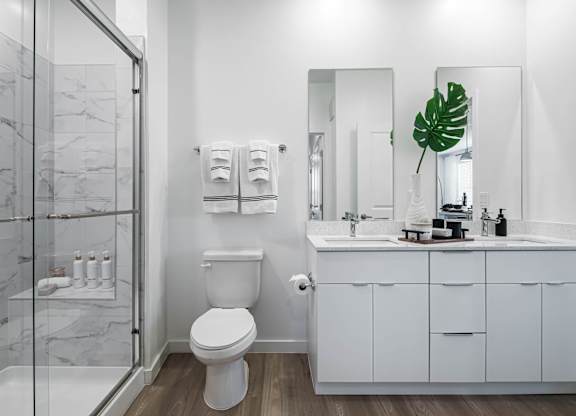 A white toilet sits in a bathroom with a marble floor and a glass shower.