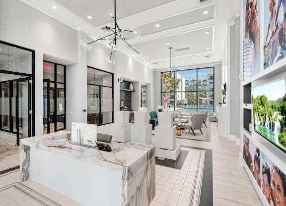 A modern office lobby with a reception desk and a large screen on the wall.