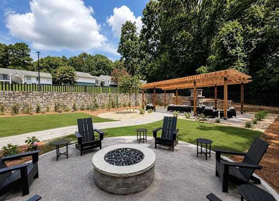 A backyard with a fire pit and chairs.