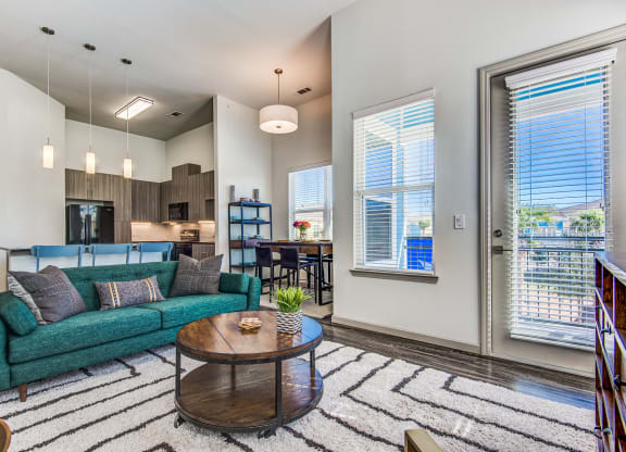 Apartments in Lewisville TX - Hebron 121 Station - Well Lit Living Room with Attached Private Balcony, Wood Plank Flooring, and Furniture