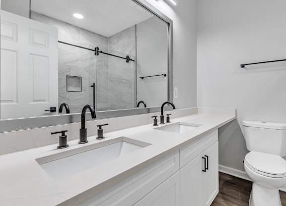 A white bathroom with a toilet, sink, and mirror.