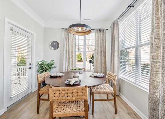 A dining room with a table set for two and a view of the backyard.