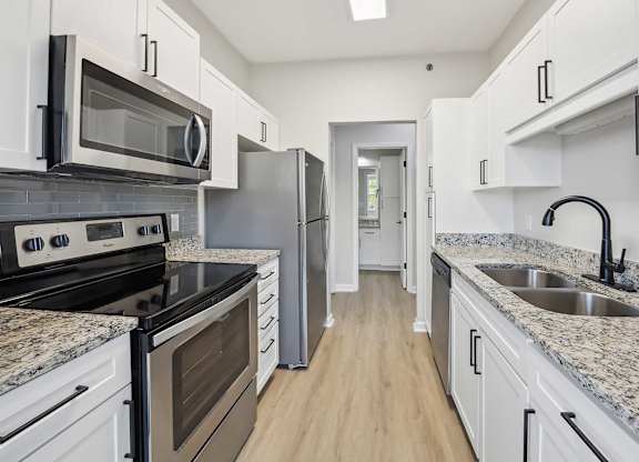 A kitchen with white cabinets and granite countertops.