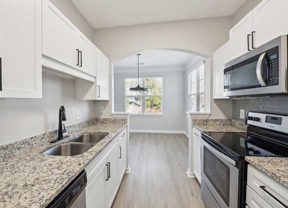 A kitchen with granite countertops and white cabinets.