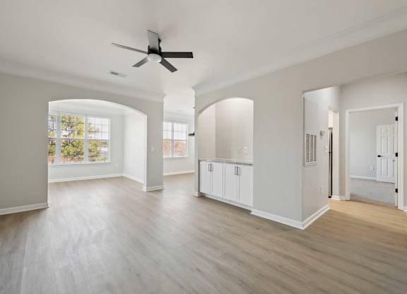 A spacious room with a ceiling fan and light wood flooring.