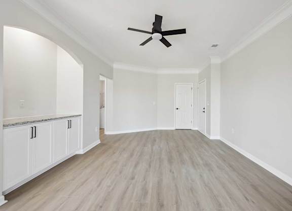 A spacious room with a ceiling fan and light wood flooring.