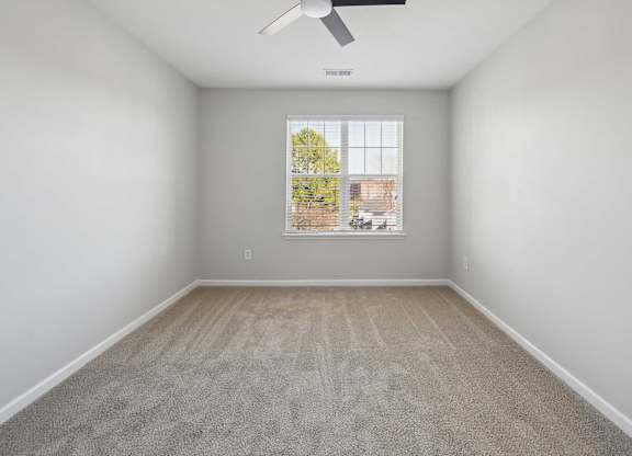 A room with a window and a fan on the ceiling.