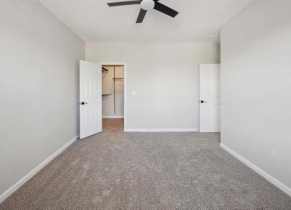 A room with a ceiling fan and carpeted floor.
