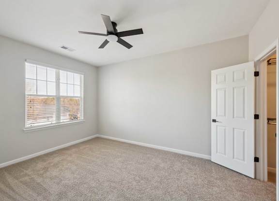 A room with a ceiling fan and a window with blinds.