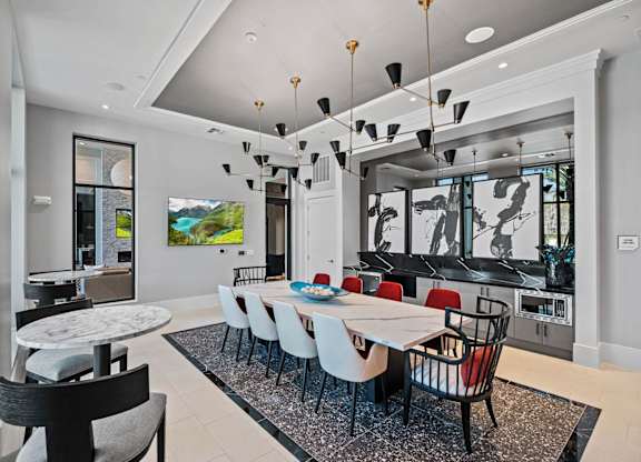 a dining room with a long white table and chairs and a kitchen in the background at Altis Twin Lakes Apartments, Kissimmee, 34744