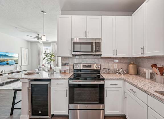 A kitchen with white cabinets and a stainless steel oven.