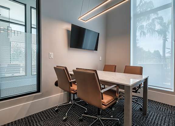 a conference room with a table and chairs and a tv at Altis Grand Suncoast, Land O' Lakes, FL