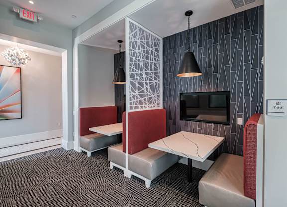 a living room with two tables and chairs and a television at Altis Twin Lakes Apartments, Kissimmee