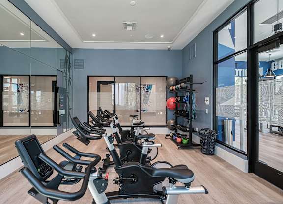 a home gym with a row of chairs in front of windows at Altis Santa Barbara, Florida