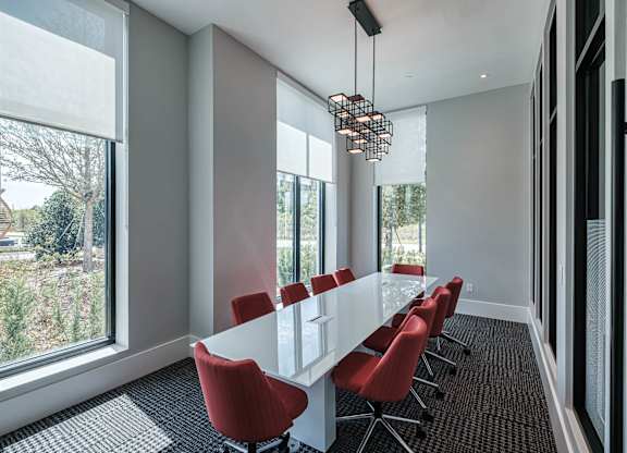 a conference room with a long white table and red chairs at Altis Grand Suncoast, Florida, 34638