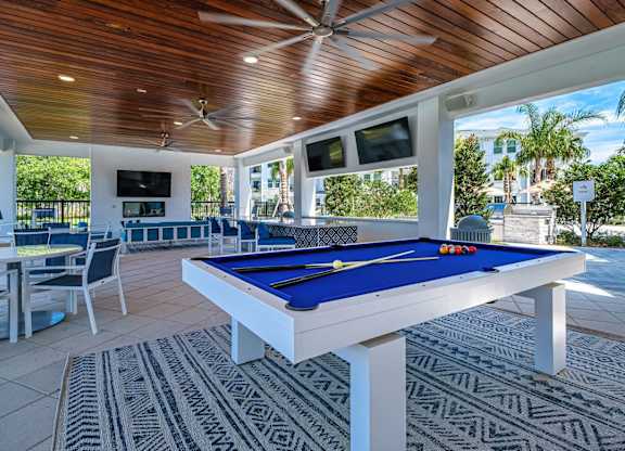 a pool table in a covered patio with tables and chairs at Altis Twin Lakes Apartments, Florida, 34744