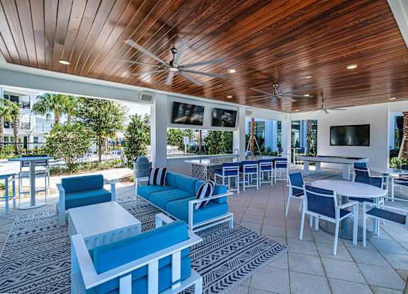 a lounge area with blue chairs and tables and a pool at Altis Grand Suncoast, Florida, 34638