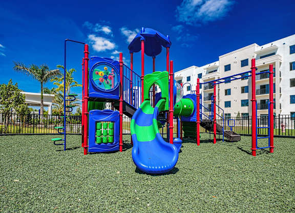 a playground with a slide and other play equipment in front of a building at Altis Santa Barbara, Naples, 34104
