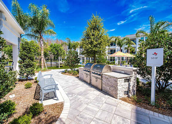 a patio with a grill and a bench next to a building at Altis Twin Lakes Apartments, Florida