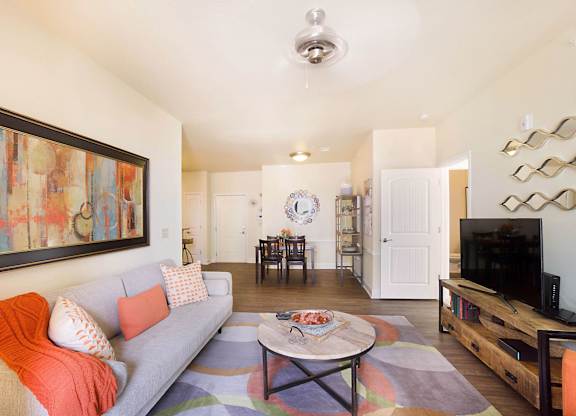 A living room with a grey couch and a painting on the wall.