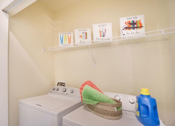A laundry room with a washer and dryer and ironing board.