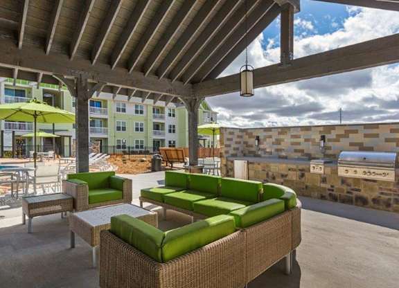 A patio with green couches and a stone wall.