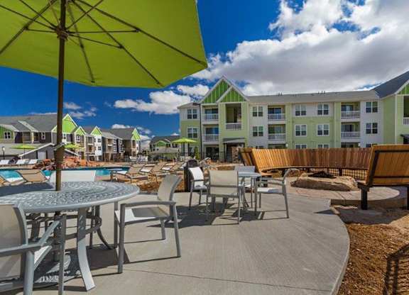 A sunny day at the poolside with a green umbrella providing shade.