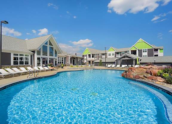 A large swimming pool in front of a building with a green roof.