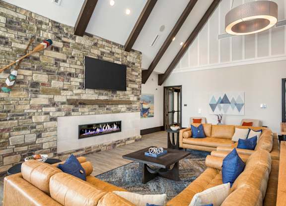 A living room with a stone fireplace and a flat screen TV mounted on the wall.