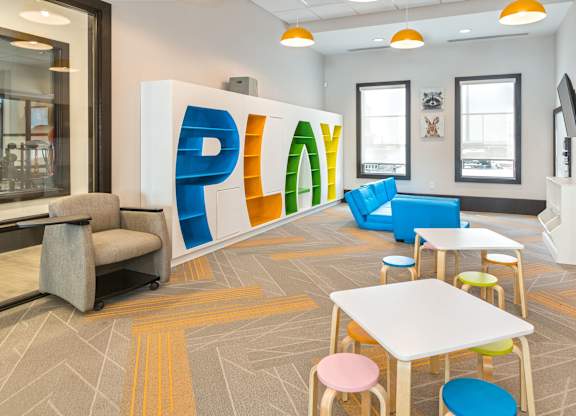 A room with a white table and chairs and a large PLAY sign.
