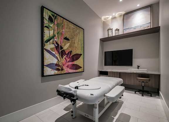 a spa room with a massage table and a tv at Altis Santa Barbara, Florida, 34104