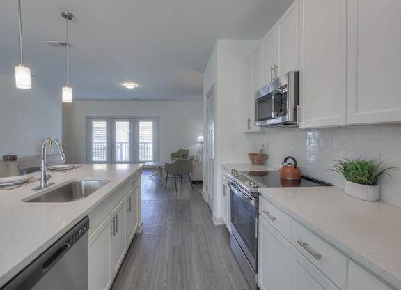 A modern kitchen with white cabinets and a wooden floor.
