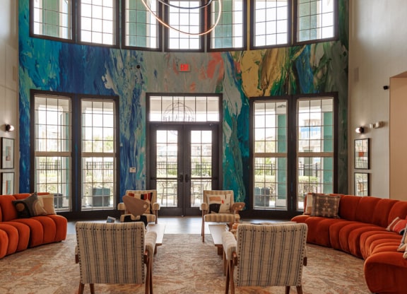 a living room with orange couches and chairs and a large wall mural