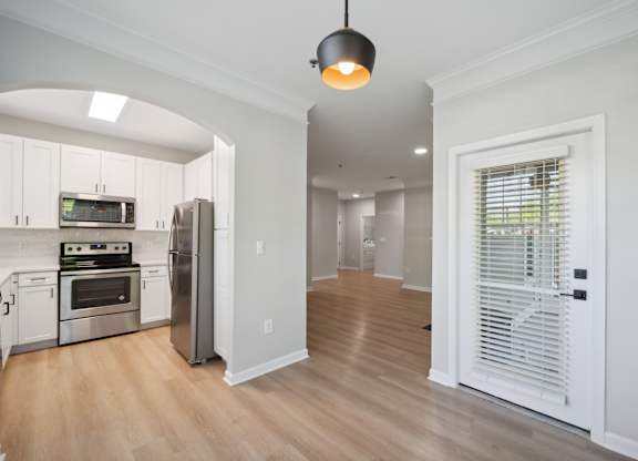 a renovated kitchen and living room with white cabinets and a door to a hallway