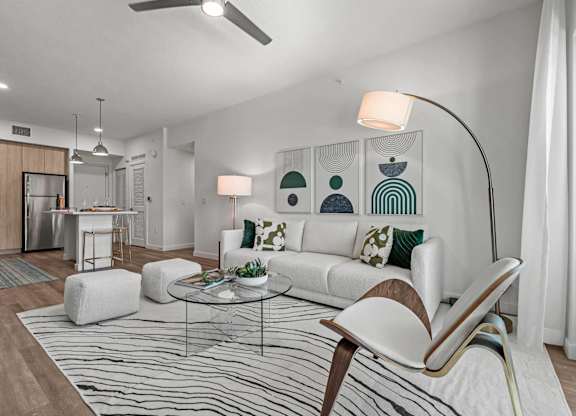 A modern living room with a white sofa, a glass coffee table, and a striped rug.
