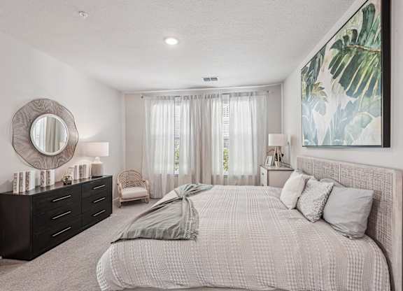 A bedroom with a large bed, a mirror, and a painting on the wall.
