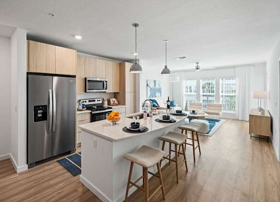 a kitchen and living room with a large island with stools at Altis Grand Suncoast, Land O' Lakes, 34638