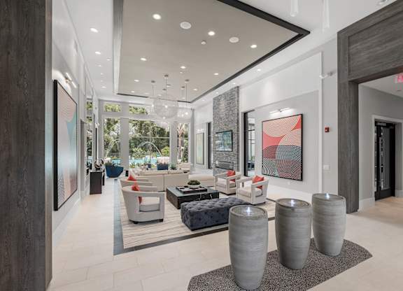 A modern living room with a large window, a couch, and a painting on the wall.
