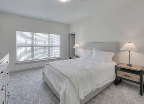 A bedroom with a large bed and a nightstand with a lamp.