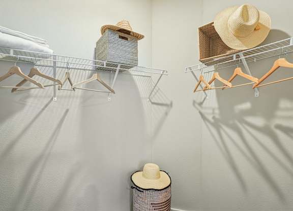 A wall-mounted clothing rack with hats and a spool of thread.