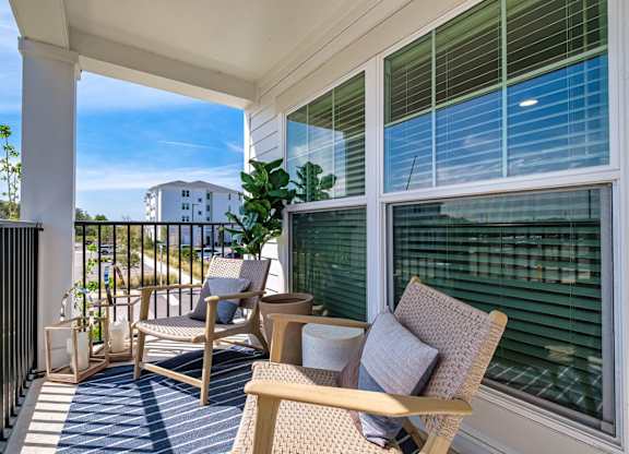 a balcony with two chairs and a table and a window at Altis Twin Lakes Apartments, Florida, 34744
